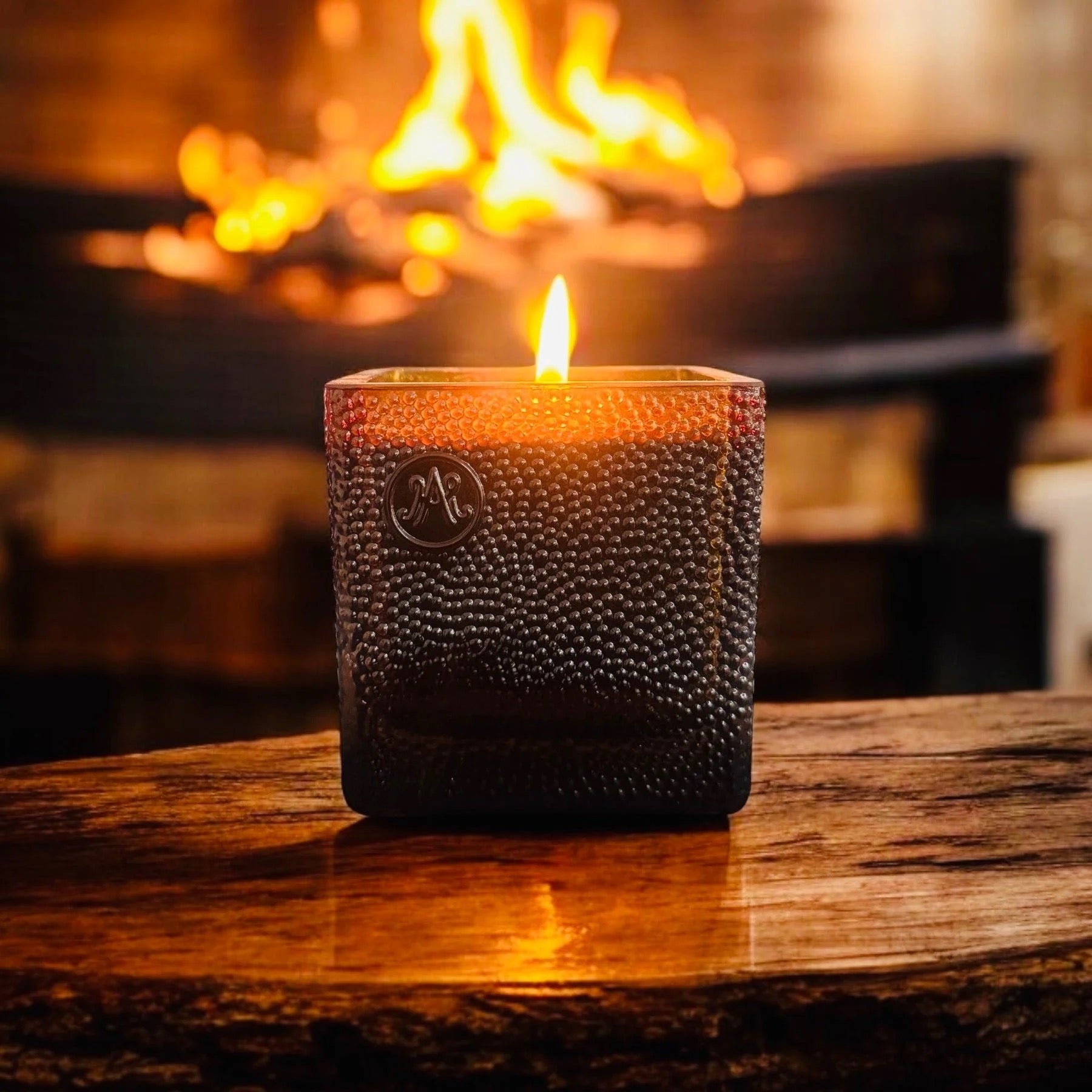 Candle burning in front of fireplace on wood table