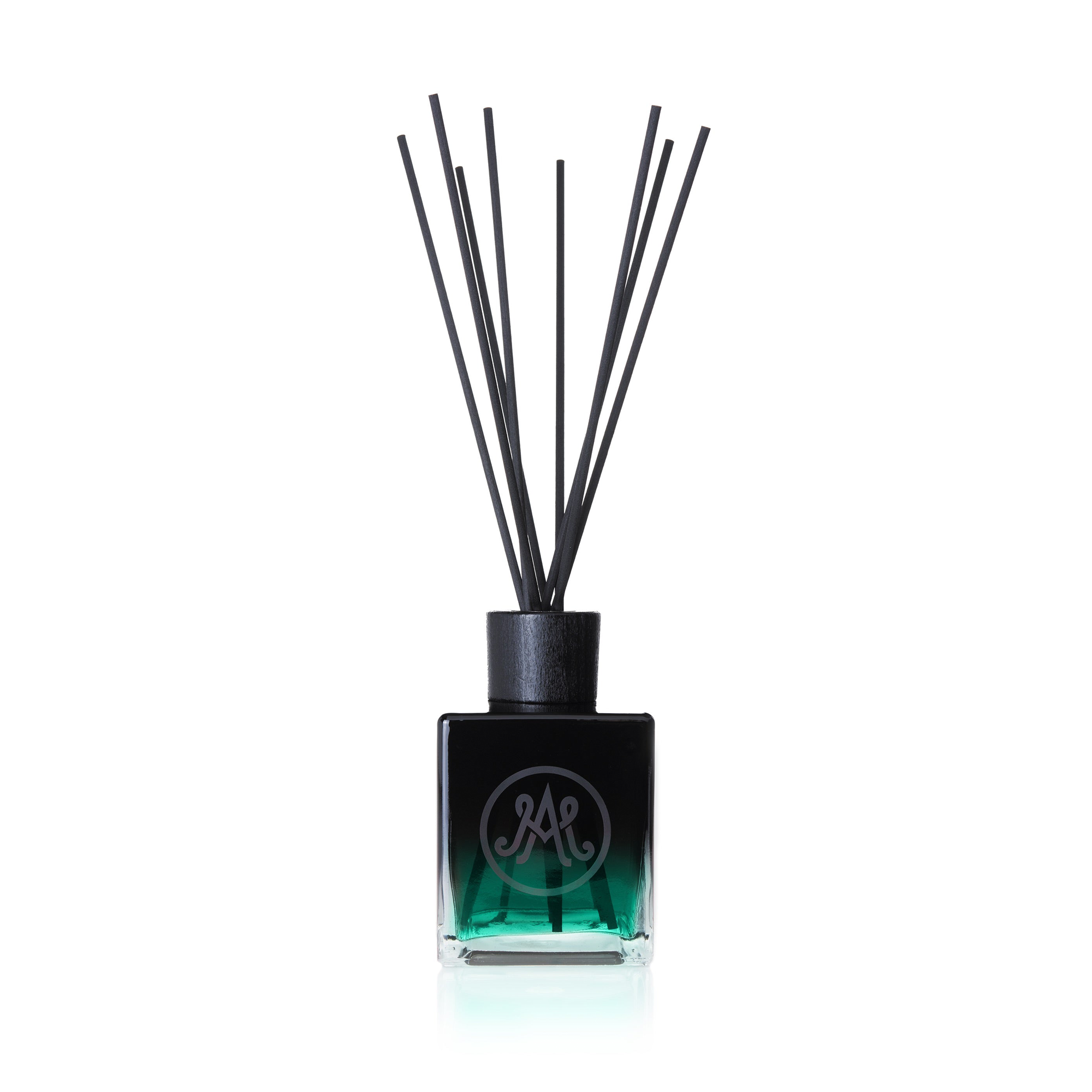 A dark green diffuser with black reeds is displayed, featuring a sleek black cap and an elegant monogram logo on the front of the bottle. A drop of 20-year-old Armagnac, with its woody, velvet aroma, adds a hint of warmth, is creating a deep, smoky, and woody scent.
