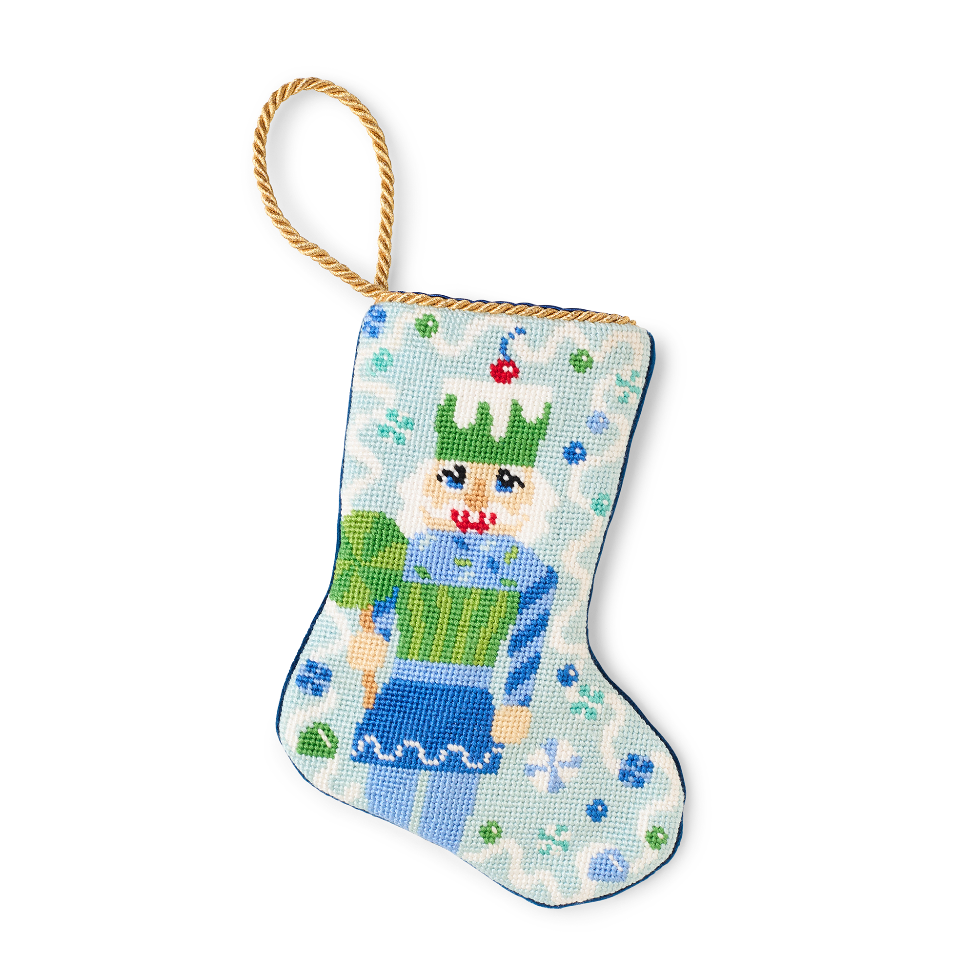 A charming Christmas stocking, featuring an illustrated Sugary Sweet Nutcracker in blue in a festive holiday scene. A gold loop at the top, is making it perfect as tree ornament, place setting, or for hanging by the fireplace.