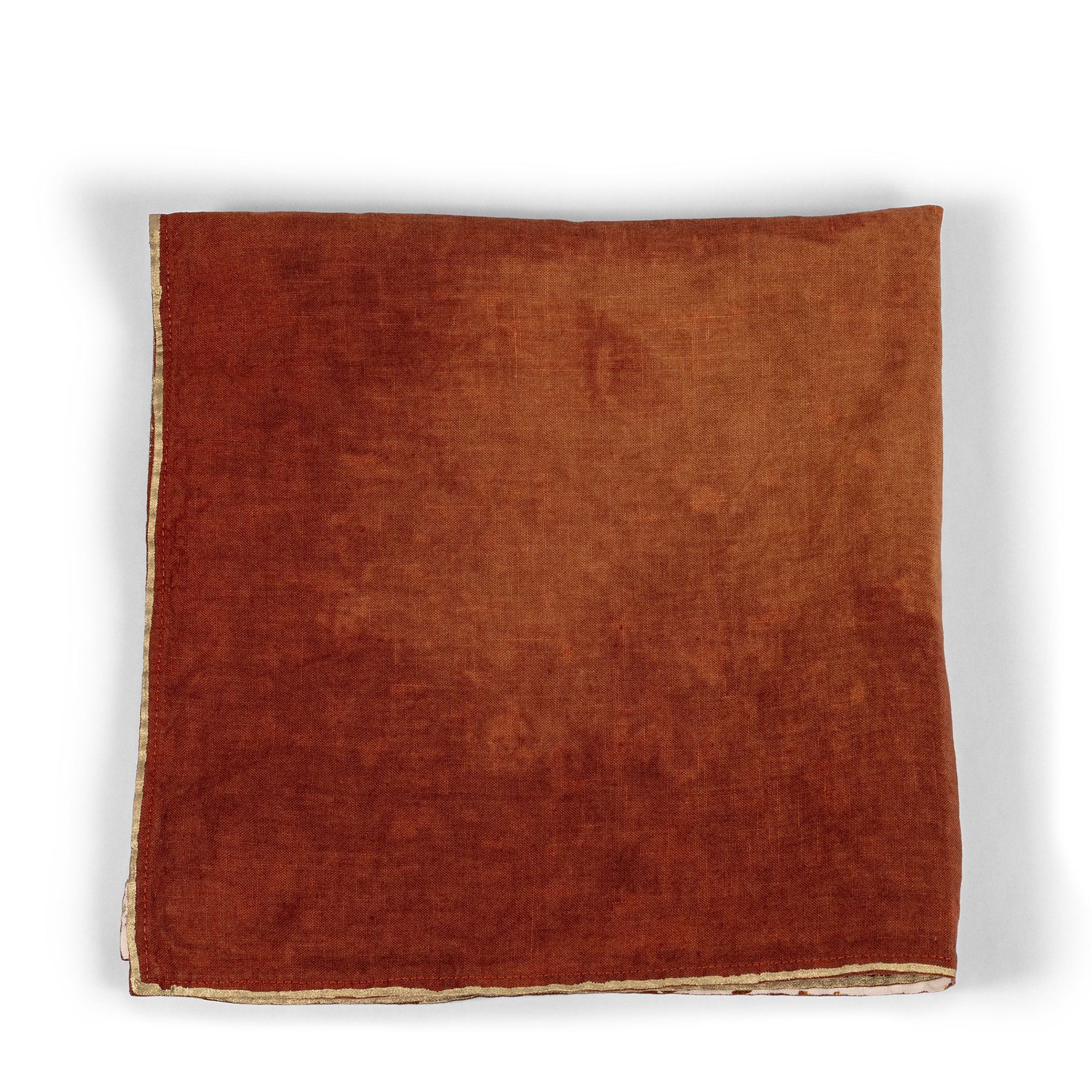 A luxurious burnt orange linen napkin with a gold-dipped edge, perfect for adding a touch of elegance and warmth to any table setting.