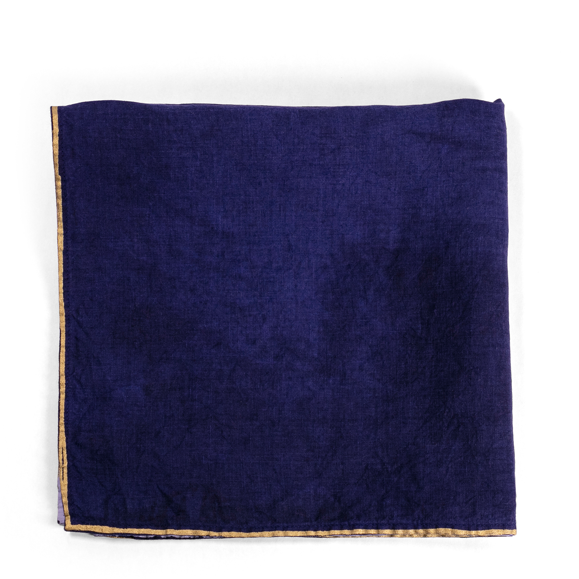A luxurious indigo linen napkin with a gold-dipped edge, perfect for adding a touch of elegance and contrast to any table setting.