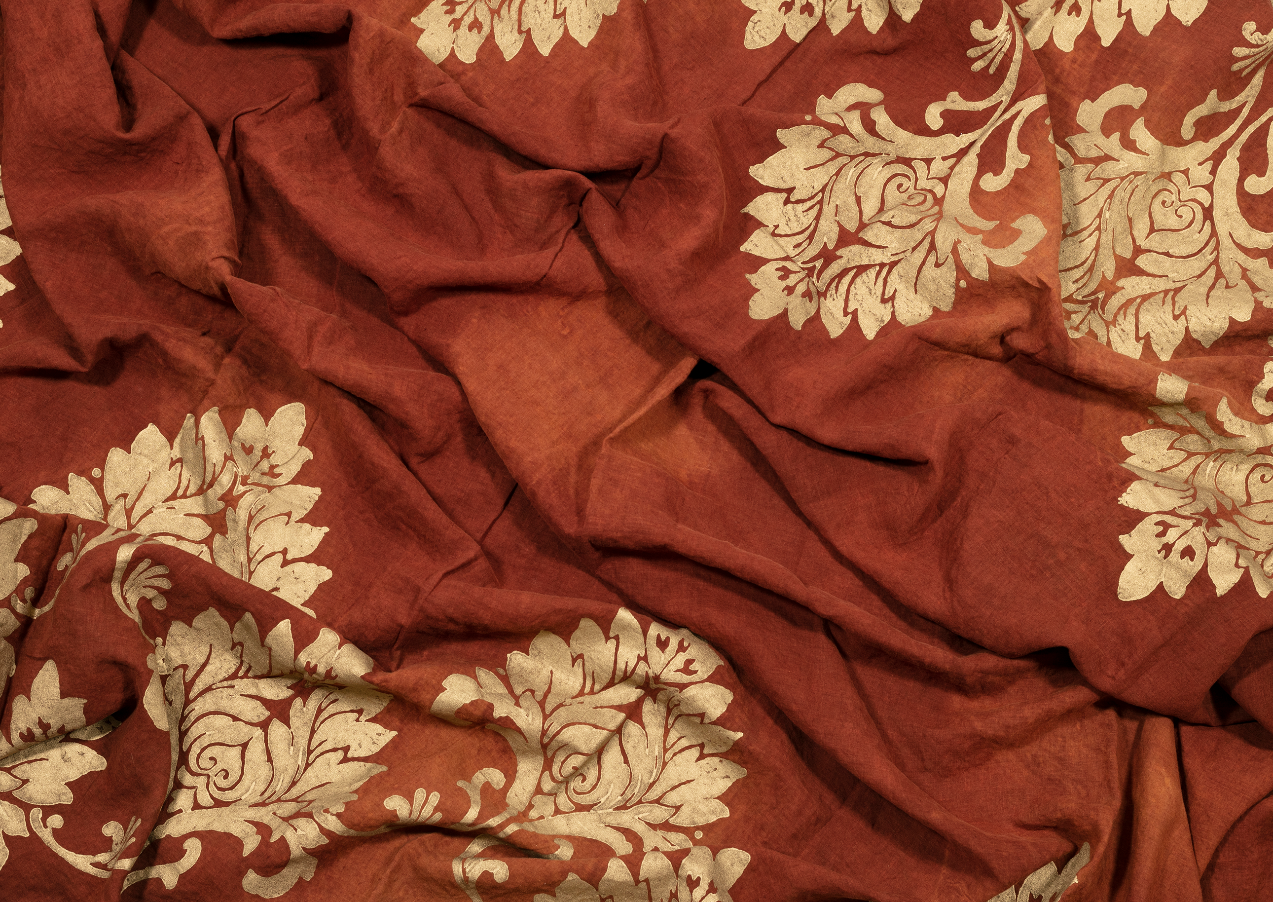 The earthy, burnt orange linen of this tablecloth is complemented by gold ornamental motifs. This striking combination adds a touch of elegance to any meal.