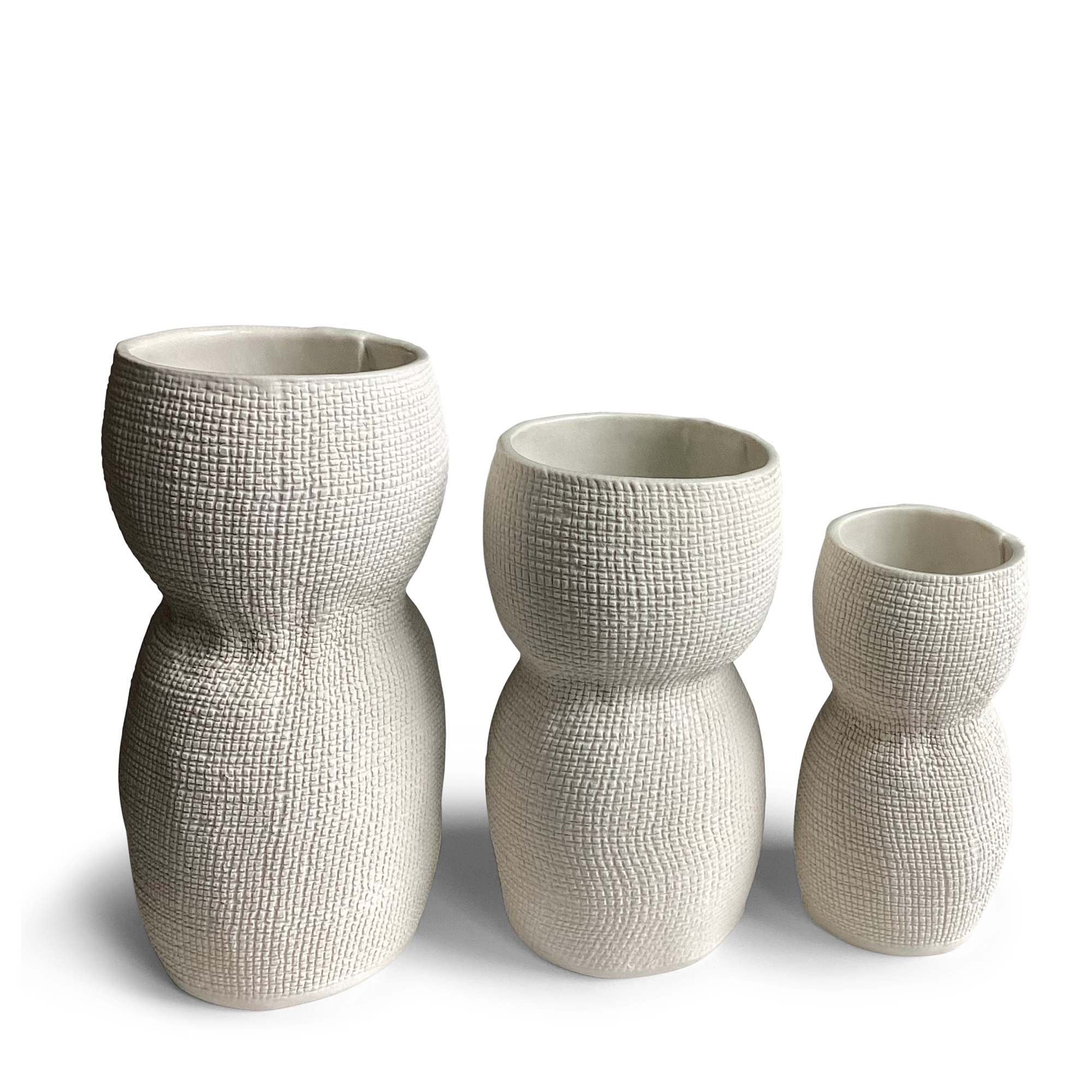 Three textured white vases of varying heights are displayed side by side, each featuring a unique, organic shape. The vases have a woven-like surface pattern that adds visual interest and a tactile feel. Their modern, sculptural design makes them perfect for minimalist or contemporary decor.